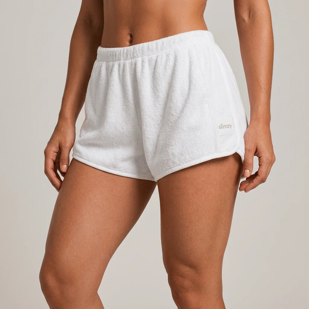 White Slimzy women's plush terry cloth loose-fit shorts laid flat, showing comfortable, casual activewear style.
